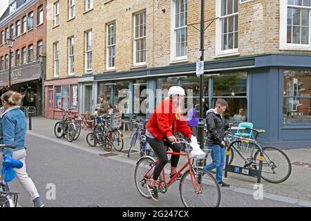 Frau, die vor dem Briki Restaurant und dem Exmouth Market Straßenschild auf dem Gebäude in Clerkenwell Islington London EC1 England Großbritannien KATHY DEWITT mit dem Fahrrad unterwegs ist Stockfoto