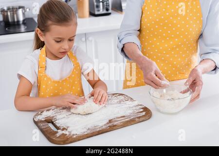 Kind macht Teig in der Nähe Oma mit Mehl in der Küche Stockfoto