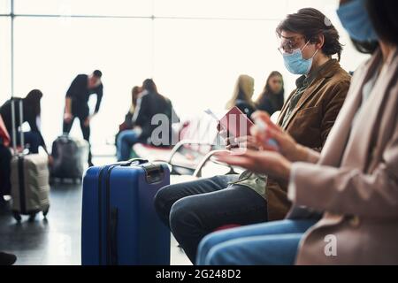 Passagiere, die während einer Pandemie auf den Flug am Flughafen warten Stockfoto