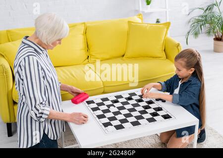 Kind und Großeltern spielen Dame Spiel an Bord Stockfoto