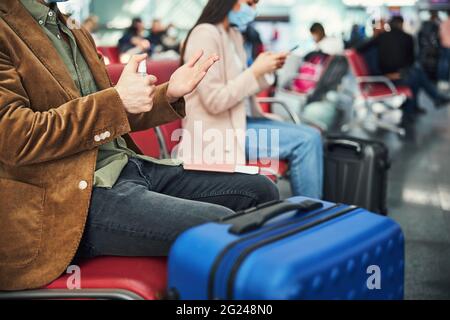 Stilvoller junger Mann, der am Flughafen Handdesinfektionsmittel verwendet Stockfoto