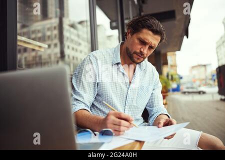 Seriöse männliche Person, die an seinem Geschäftsplan arbeitet Stockfoto