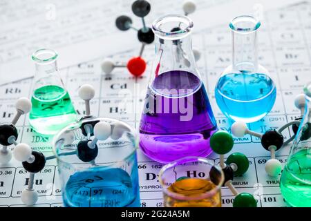 Molekulare Modelle und Laborglaswaren mit Flüssigkeiten auf Periodensystem Stockfoto