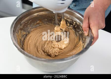 Nahaufnahme eines zugeschnittenen Bildes von einer Frau, die Kuchenzutaten mit einem Küchenmixer mischte. Stockfoto