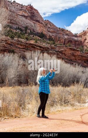 USA, Utah, Escalante, Frau, die beim Wandern im Grand Staircase-Escalante National Monument Fotos macht Stockfoto