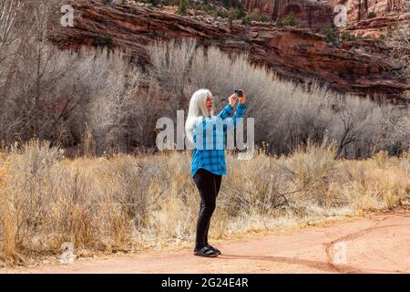 USA, Utah, Escalante, Frau, die beim Wandern im Grand Staircase-Escalante National Monument Fotos macht Stockfoto