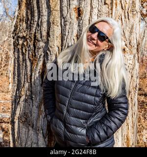 Porträt einer älteren Frau, die vor einem Baumwollholzbaum steht Stockfoto