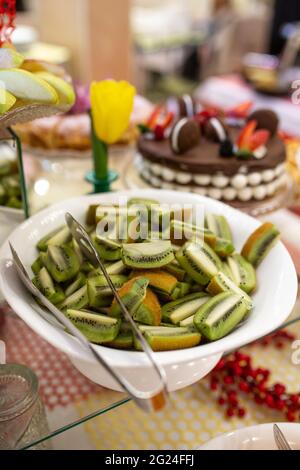 Kiwi-Stücke auf einem weißen Teller auf einem Buffettisch. Stockfoto