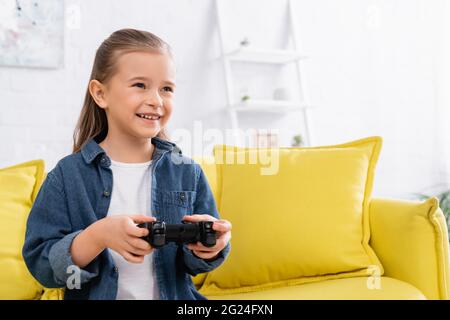 KIEW, UKRAINE - 11. JANUAR 2021: Glückliches Mädchen mit Joystick, das Videospiel auf der Couch spielt Stockfoto