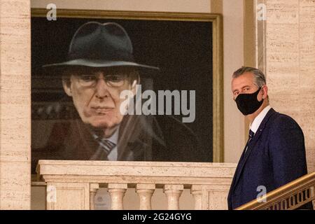 DUP-Chef Edwin Poots geht in den Hallen der Parlamentsgebäude an einem Porträt des ehemaligen Parteiführers Ian Paisley vorbei, um einen Teil seines ersten Ministerteams in Stormont anzukündigen. Stockfoto