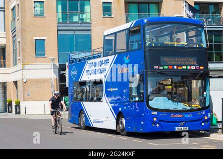 Mann fährt im Mai mit dem Fahrrad am Hop-on-Hop-off-Doppeldeckerbus von Golden Tours in Poole, Dorset, Großbritannien, vorbei Stockfoto