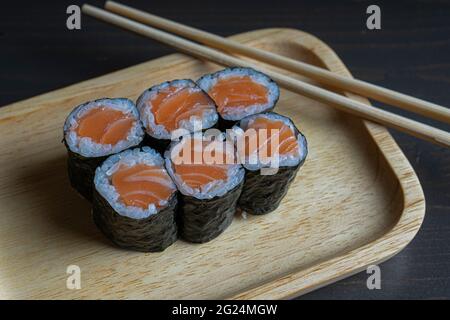 Maki rollt mit geräuchertem Lachs auf einem Holzteller Stockfoto