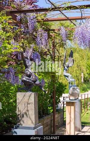 Skulpturen, Statuen und Glyzinien bei Sculpture by the Lakes, Pallington Lakes, Dorchester, Dorset UK im Juni Stockfoto