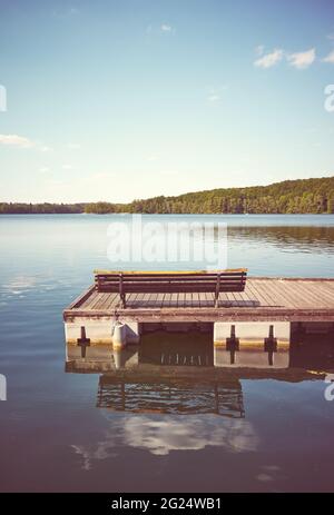 Bank auf einem hölzernen schwimmenden Pier, Farbtonung angewendet, Lipie-See in Dlugie Village, Polen. Stockfoto