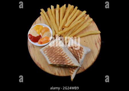 Französische Tacos mit Huhn. Serviert mit pommes Frites, Mayonnaise, Ketchup und Senf auf schwarzem Hintergrund Stockfoto