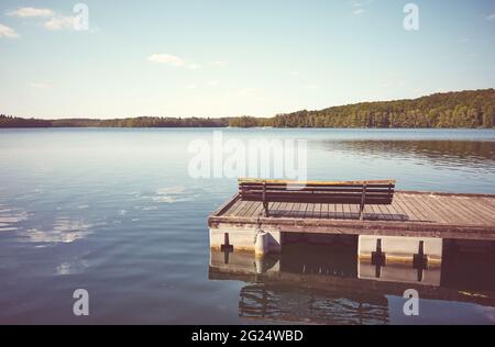 Bank auf einem hölzernen schwimmenden Pier, Farbtonung angewendet, Lipie-See in Dlugie Village, Polen. Stockfoto