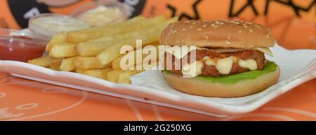 Draufsicht auf pommes Frites mit köstlichem Burger-Chicken-Tablett und verschiedenen Saucen Stockfoto