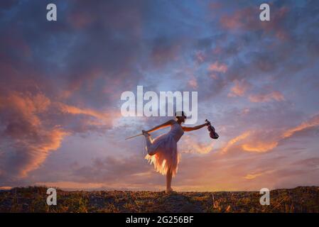 Frau, die bei Sonnenuntergang auf einem Bein im Freien steht und eine Geige hält, Thailand Stockfoto