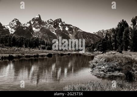 Schwarz-Weiß-Fotografie von Schwabachers Landung mit Spiegelung der Grand Teton-Bergkette auf dem flachen Wasser des Snake River, in Jackson Hole, WY. Stockfoto