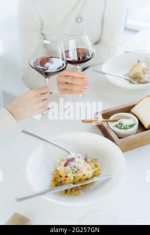 Zwei Frauen, die in einem Restaurant einen festlichen Toast mit Rotwein machen Stockfoto