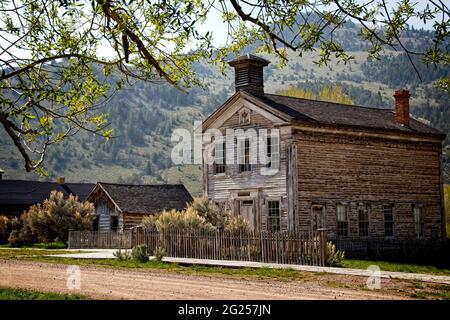 Holzabsperrungen auf Freimaurerloge und Schulhaus in Bannack, Montana Geisterstadt; auch Blockhütte, Pfostenzaun, Holz Bürgersteig, Unbefestigte Straße und Baum. Stockfoto