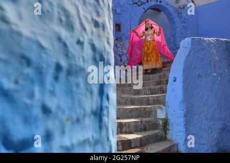 Frau in traditioneller Kleidung, die die Treppe hinunter geht, Chefchaouen, Marokko Stockfoto