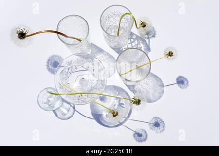 Sommerstill-Szene. Glitzernde Gläser Wasser oder Cocktails auf weißem Tischhintergrund bei Sonnenlicht. Lange harte Schatten. Urlaubskonzept Stockfoto