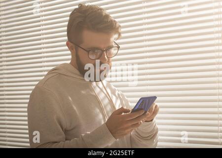 Glücklicher Mann, der zu Hause oder im Büro mit dem Mobiltelefon telefoniert Stockfoto
