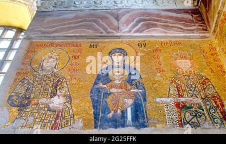 Detail des Comnenus-Mosaiks, Hagia Sophia (türkisch: Ayasofya), Istanbul, Türkei. Die Jungfrau Maria in einem dunkelblauen Kleid hält das Christkind auf ihrem Schoß. Er segnet mit seiner rechten Hand, während er eine Schriftrolle in seiner linken hält. Auf ihrer rechten Seite steht Kaiser Johannes II. Comnenus, der eine Geldbörse hält, das Symbol einer kaiserlichen Schenkung an die Kirche. Gegenüber steht seine Frau, die Kaiserin Irene von Ungarn, in zeremoniellen Gewändern und mit einem Dokument. Byzantinische Kunst Stockfoto