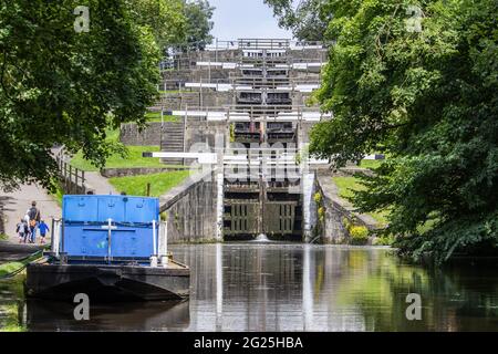 Ein Lastkahn wartet am Fuße der fünf-ragen Schleusen in Bingley am Leeds & Liverpool Kanal in West Yorkshire, England Stockfoto