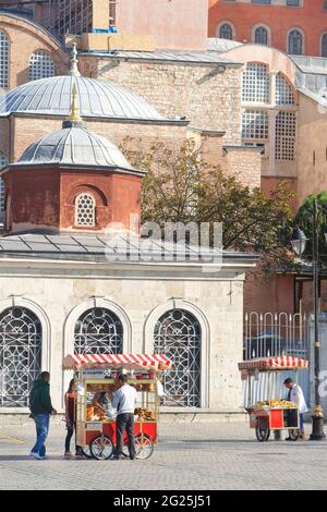 Stände mit gedünsteten Nüssen und anderem Essen an Touristen vor der Hagia Sophia (türkisch: Ayasofya), offiziell Ayasofya-i Kebir Cami-i ?erifi buchstäblich Heilige Moschee der Hagia Sophia der große, und früher die Kirche der Hagia Sophia. Istanbul, Türkei