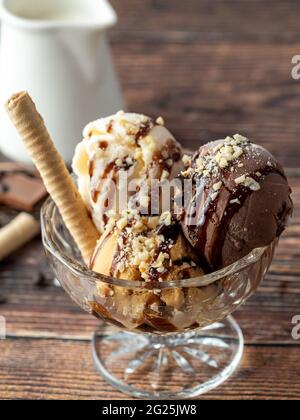 Schokolade, Rahm und Karamell-Roma-Eis in einer Glasschüssel mit Haselnuss- und Schokoladensauce darüber gegossen. Stockfoto