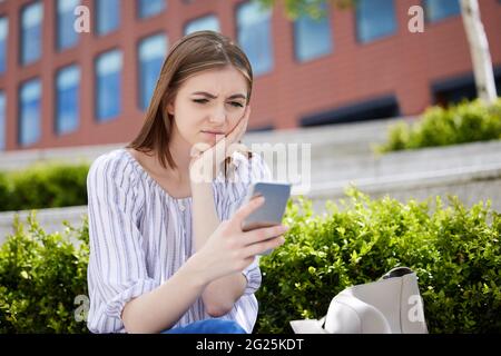 Unglückliche Junge Frau Mit Mobiltelefon, Das Online Auf Dem Campus Der Universität Schikaniert Wird Stockfoto