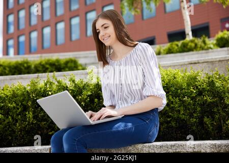Junge Weibliche College-Studentin Mit Laptop, Die Auf Dem College Campus Im Freien Arbeitet Stockfoto