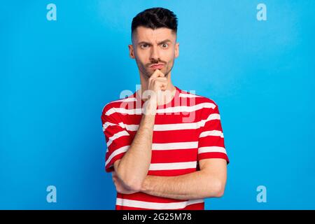 Foto von ernsthaft gesinnten jungen Mann halten Hand Kinn Zweifel Frage isoliert auf blauem Hintergrund Stockfoto