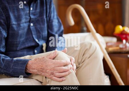 Nahaufnahme Eines Älteren Mannes, Der Zu Hause Auf Dem Sofa Sitzt Und An Knieschmerzen Durch Arthritis Leidet Stockfoto