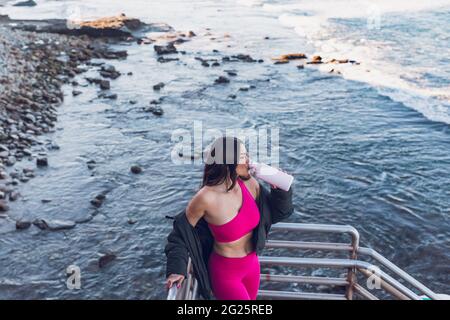 Brunette Frau trägt rosa Trainingskleidung Trinkwasser. Stockfoto