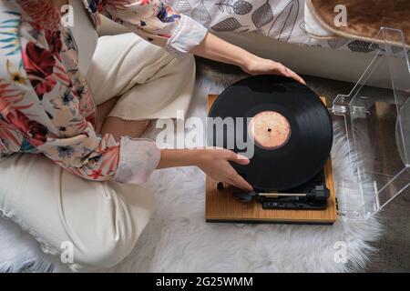 Nicht erkennbare Frau, die eine Schallplatte auf einen Plattenspieler legt Stockfoto