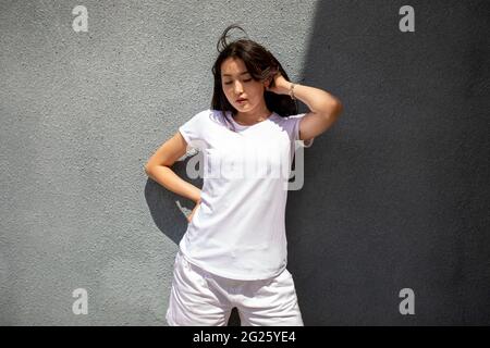 Asiatische Frau in weißem T-Shirt und roter Sonnenbrille. Modell. Stockfoto