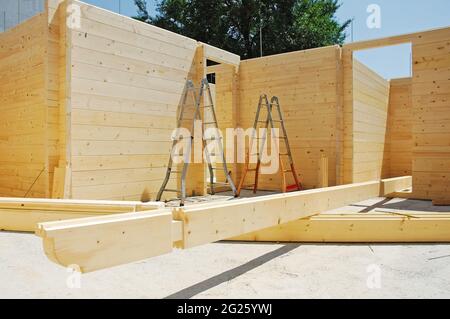 Leitern in einem teilweise gebauten Blockhaus aus Holz (Tanne), einem vorgeschnittenen Holzhaus, das vor Ort montiert wird. Einige der Dachträger befinden sich auf dem Boden Stockfoto