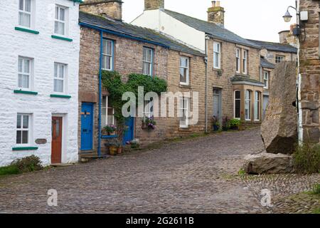 Die malerischen gepflasterten Straßen im Dorf der Einbuchtung, in Dentdale, Cumbria. Stockfoto