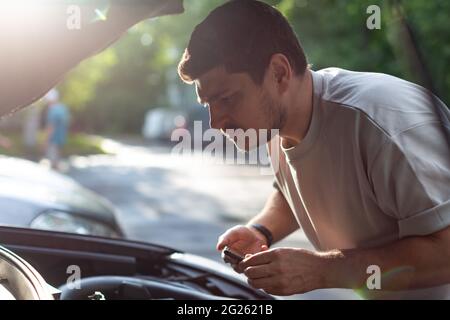 Ein Mann auf einer Stadtstraße überprüft den Betrieb des Autos, schaut unter Th Stockfoto