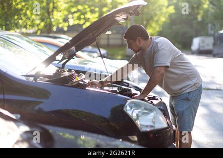 Ein Mann auf einer Stadtstraße überprüft den Betrieb des Autos, schaut unter Th Stockfoto