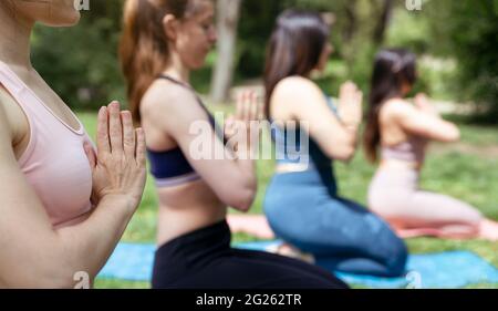 Nahaufnahme der Hände einer Frau, die in der Natur Gruppenyogas praktiziert. Selektiver Fokus. Stockfoto