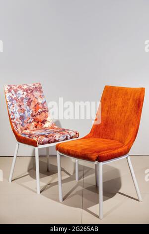 Moderne orangefarbene Sessel mit Velours-Polsterung und Beinen aus weißem Metall Stockfoto