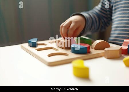 Lernspielzeug, kognitive Fähigkeiten, Montessori-Aktivität. Nahaufnahme: Hände eines kleinen Montessori-Kindes, das über Farbe, Form, Sortieren, Ordnen lernt Stockfoto