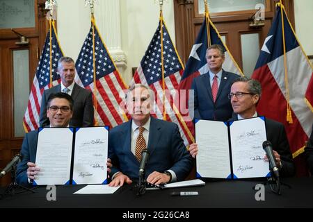 Austin TX USA, Juni 8 2021: Texas Gov. Greg Abbott posiert nach der Unterzeichnung von zwei Gesetzesvorlagen zur Stärkung des texanischen Stromnetzes und der Infrastruktur, die als Notfälle auf seiner legislativen Tagesordnung standen. Die Gesetzesvorlagen waren eine Reaktion auf den Wintersturm im Februar, der Teile des texanischen Stromnetzes ausschlug und Millionen von Texanern tagelang ohne Strom auskam. Links sehen Sie Rep. Chris Paddie, R-Marshall, rechts Senator Kelly Hancock, R-North Richland Hills. Kredit: Bob Daemmrich/Alamy Live Nachrichten Stockfoto