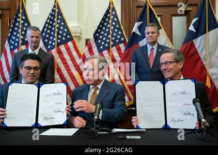 Austin TX USA, Juni 8 2021: Texas Gov. Greg Abbott posiert nach der Unterzeichnung von zwei Gesetzesvorlagen zur Stärkung des texanischen Stromnetzes und der Infrastruktur, die als Notfälle auf seiner legislativen Tagesordnung standen. Die Gesetzesvorlagen waren eine Reaktion auf den Wintersturm im Februar, der Teile des texanischen Stromnetzes ausschlug und Millionen von Texanern tagelang ohne Strom auskam. Links sehen Sie Rep. Chris Paddie, R-Marshall, rechts Senator Kelly Hancock, R-North Richland Hills. Kredit: Bob Daemmrich/Alamy Live Nachrichten Stockfoto