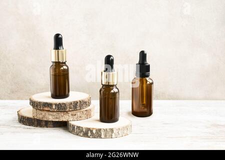 Tropfflaschen aus Glas für medizinische und kosmetische Anwendungen für gesunde Hautpflege auf Holzschnitt. Naturkosmetik und umfangreiche Öko-Verpackungen, SPA-Konzept. Stockfoto