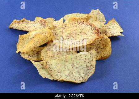 Haufen knackiger Taro-Gemüsechips mit Meersalz auf blauem Hintergrund Stockfoto